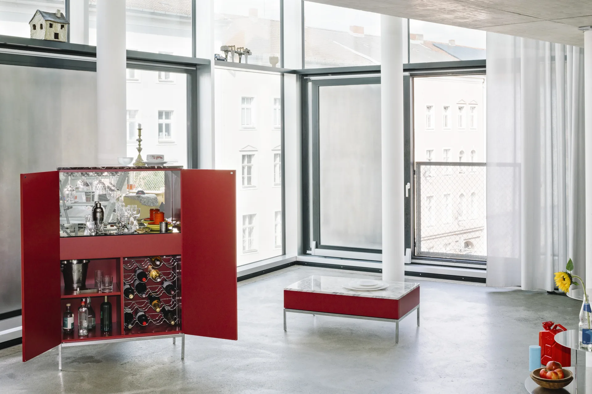 Knoll Chermayeff Storage bar cabinet in red lacquer, open, with glasses and a wine rack, in a loft