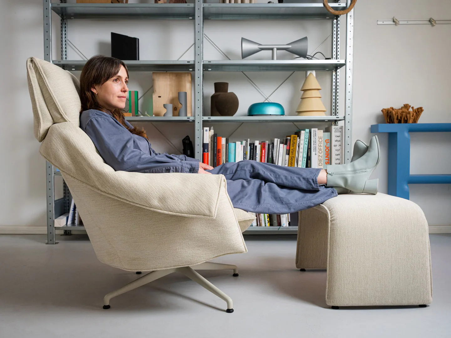 Vitra Bascule Highback lounge chair with ottoman, reclined, in a room with open shelving